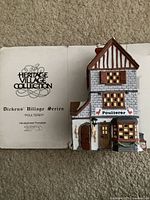 Color photo of porcelain Poulterer building in front of the Heritage Village Collection box showing the logo and details.
