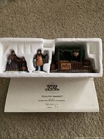 Set of three Heritage Village Collection figurines and poultry market stall in original white styrofoam packaging with box underneath.