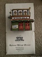 Color photo of the Theatre Royal porcelain building with the original box placed underneath it showing the front facade of the building.