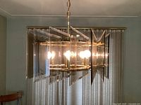Chandelier illuminated, showing brass frame and smoked glass panels