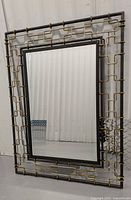 Full view of the decorative metal framed mirror showing the geometric metal design surrounding the rectangular mirror glass.