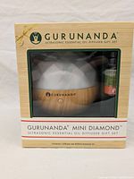 Front of the boxed Gurunanda Mini Diamond Ultrasonic Essential Oil Diffuser Gift Set showing product through plastic window and branding