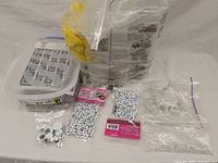 Photo showing plastic container and packs of googly eyes and other items on a white surface.