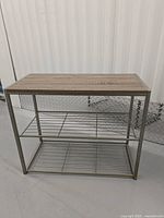 Front view of shoe rack showing wooden top surface and two metal wire shelves.