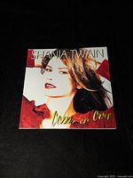 Front cover of 'Come On Over' album showing Shania Twain's portrait in red clothing.