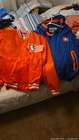 Orange Denver Broncos satin jacket with snap buttons and logo on chest, striped collar and cuffs.