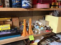 Shelf showing assorted candle boxes and two tall orange decorative candle holders.