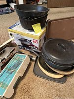 Overview of all cast iron pots, frying pan, fajita plates, serving heat pad, and Wearever pot with box.