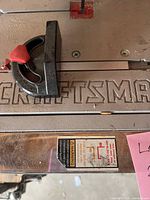 Top-down view of saw table showing embossed Craftsman logo, blade slot, fence and warning label.
