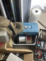 Blue metal tackle box, beige net, spool of line, cardboard boxes of lures