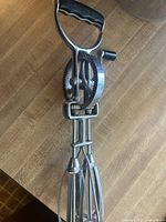 Vintage handheld rotary egg mixer with metal gears and dual wire beaters, showing black plastic handle marked 'MAYNARD'.