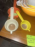 Photo showing plastic strainers and some Pyrex bowls stacked in the background.