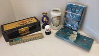 Full assortment of Asian decorative items including vases, boxes, fan, egg, and bags arranged on flat surface