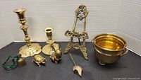Brass items including candle holders, small animal figurines, a picture holder stand, and a brass bowl.