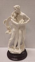 Front view of couple statue showing emotional embrace and detailed floral base.