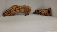 Both Coho salmon and Raven carvings side by side on a neutral background
