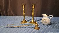 All items: pair of brass candlesticks, brass snuffer, porcelain creamer