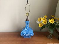 Front view of blue crater-glaze ceramic lamp with wood neck and harp