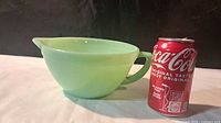 Side view of Jadeite mixing bowl beside soda can for scale