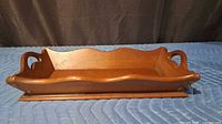 Side angle of solid cherry bread tray showing scalloped rim and handles