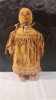 Front view of doll showing suede fringed dress, bead trim, moccasins, yarn hair and embroidered face