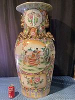 Front view of tall multicolor porcelain vase beside soda can for scale