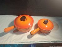 Top view of both orange Le Creuset saucepans with lids