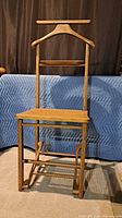 Full front view of wooden valet stand showing hanger, tray and cane seat