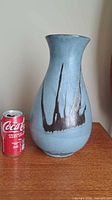 Full view of light blue and brown drip-glaze vase beside soda can for scale