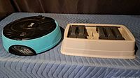 Overall view of both items: teal automatic feeder and beige puzzle tray