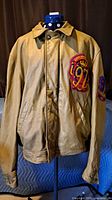 Front view of tan leather varsity jacket on stand showing overall design