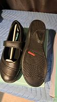 Top and sole view of black Apex Mary Jane shoe on box