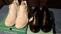 White Apex sneakers and black loafers on boxes
