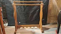 Front view of wooden quilt rack showing three rails and scalloped base