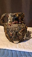 Front angled view of ceramic jug displaying dense assemblage surface