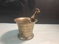 Brass mortar with pestle resting inside showing overall form and patina