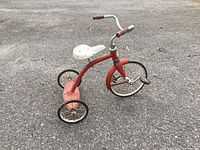 Full view of red tricycle showing frame, seat, wheels and handlebars