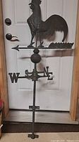 Full view of copper rooster weathervane showing arrow, directional letters, spacer ball, and mounting pole