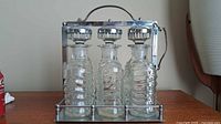 Front view of three glass decanters in chrome carrier
