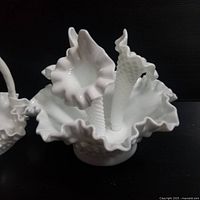 Front-side view of white Fenton milk glass epergne with three horn trumpet vases and ruffled edges on a hobnail textured bowl base, showing glossy finish and details of texture.