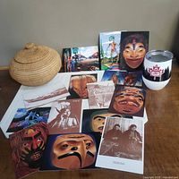 Photo showing a round woven basket, multiple First Nation art cards and postcards, and a collectible cup