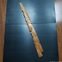 Full length view of the 33 inch wooden carving showing the overall design and condition on a black backdrop.