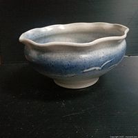 Side view of a hand potted vintage ceramic bowl showing scalloped rim and blue gradient glaze