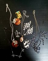 Photo showing multiple pieces of vintage and costume jewelry including necklaces and earrings arranged on a dark surface.