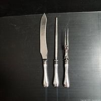 Top view of the three-piece carving set showing knife, sharpening steel, and carving fork with visible patina and wear consistent with vintage use.