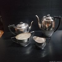 Full set of four pieces displayed on black surface: teapot, coffee pot, creamer, and sugar bowl showing overall size and style.