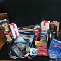 Front view of the lot showing various boxed beer glasses and small drink accessories grouped on black surface