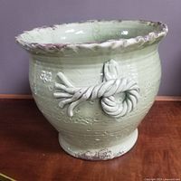 Front side view of pale green Vietnamese ceramic planter with scalloped rim and rope knot handle