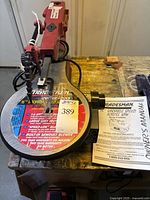 Front and top view of the red and black Tradesman 16 inch variable speed scroll saw on wood workbench, showing detailed decal and model number 8366S. Owner's manual visible.
