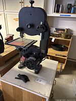 Full view of band saw mounted on cabinet with motor visible